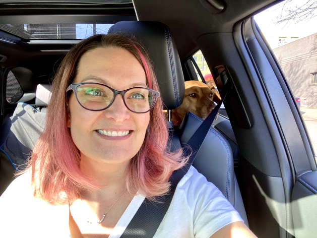 a girl with pink hair and her dog in a car