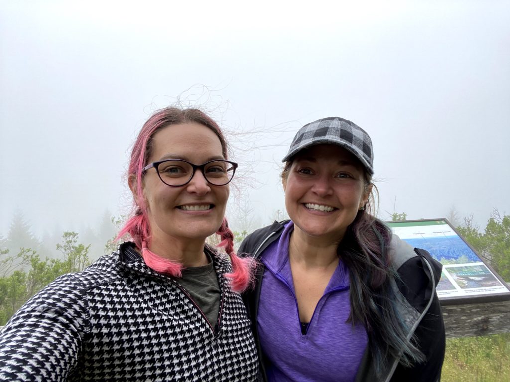 a pink haired woman and mermaid haired woman on a roadtrip in the redwoods