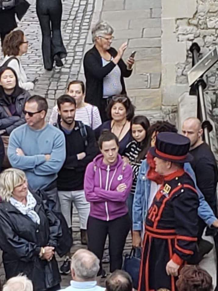 A group, including Laura in the striped shirt, gathers to hear a tour at the Tower of London.