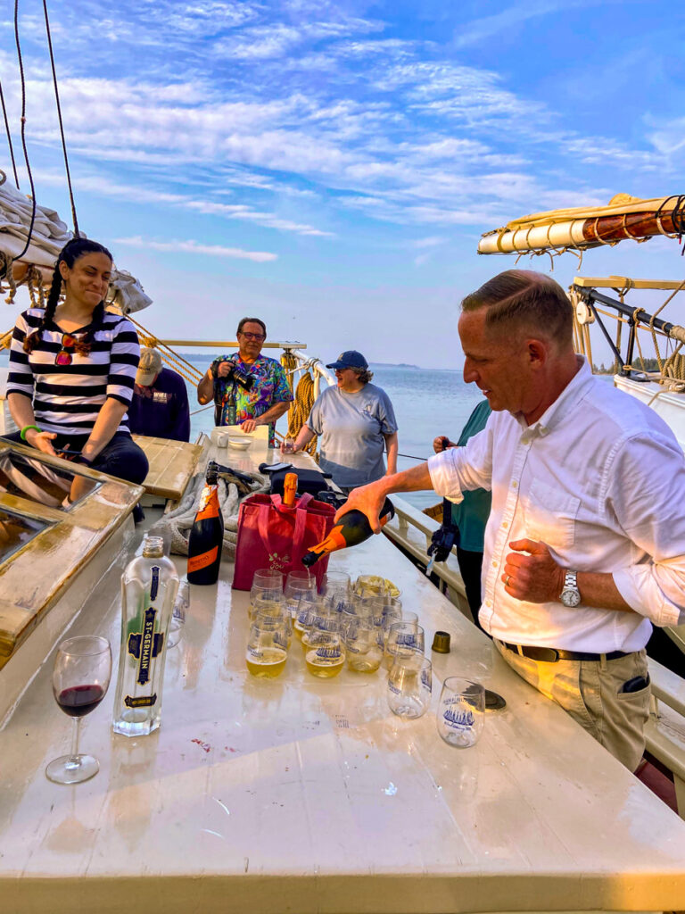 image shows several people gathering on a sailboat deck for happy hour