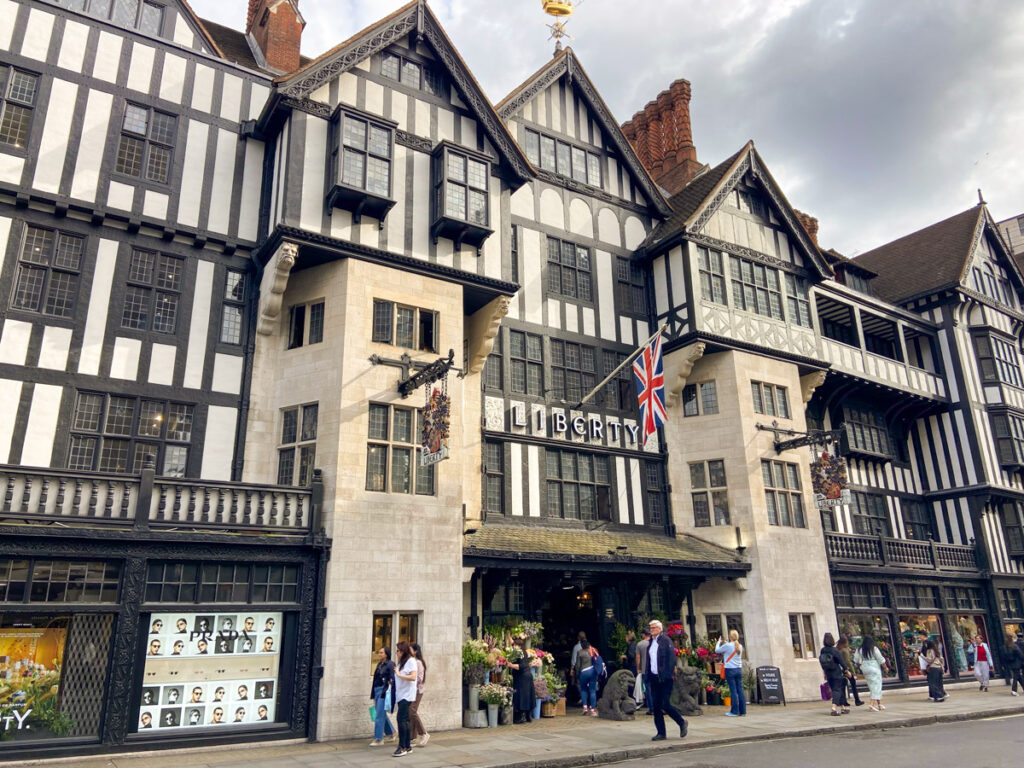 image shows Liberty of London building which resembles a Tudor style building, with whitewashed walls and wood beams. 