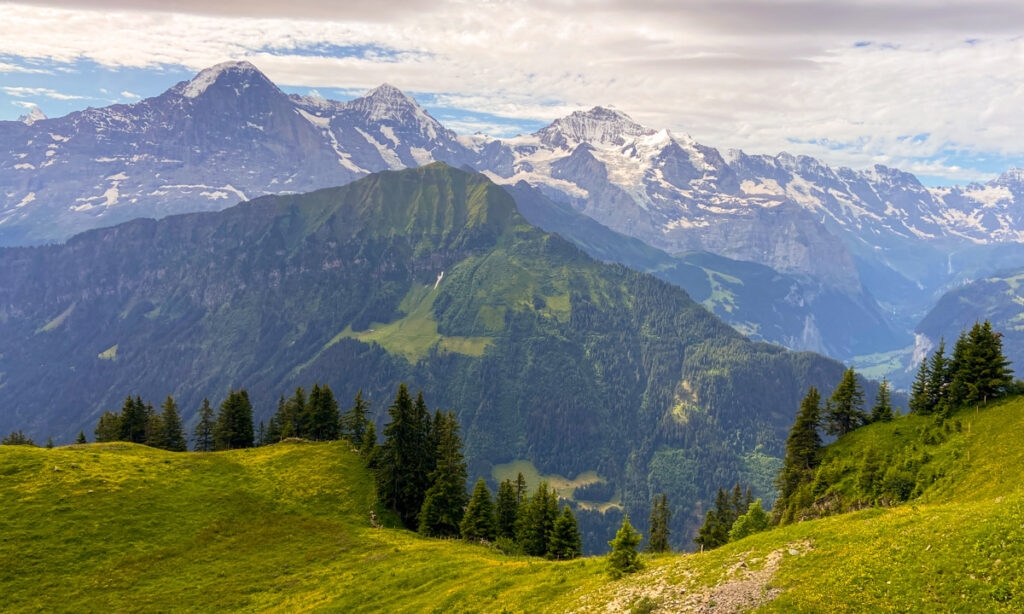 Image shows a mountain range in the swiss alps with hills in the foreground.