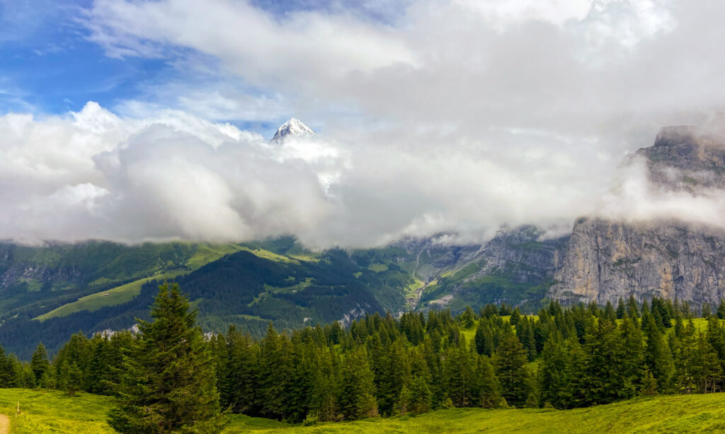 image shows the tip of a snow covered mountain peeking out from clouds in the swiss alps