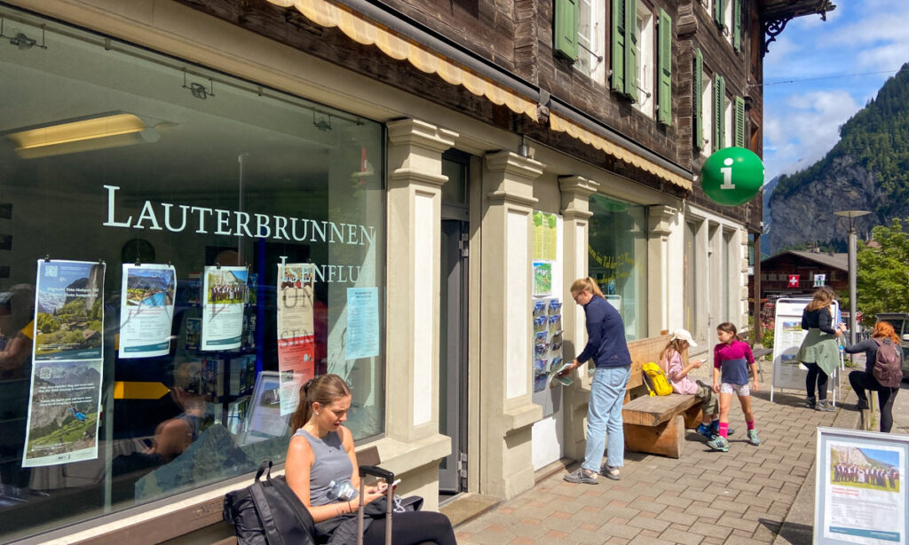 image shows a business with benches out front and people sitting on them.